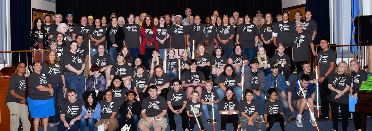 Group picture of students, staff, and volunteers sitting on stairs in auditorium