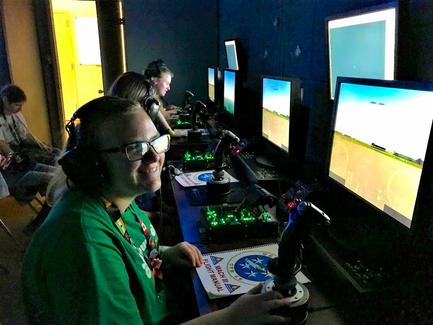 Student smiling at camera sitting at space control